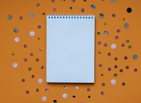 White writing pad on orange background with confetti.の写真素材