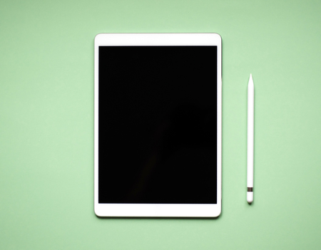 White tablet lying on solid color background.