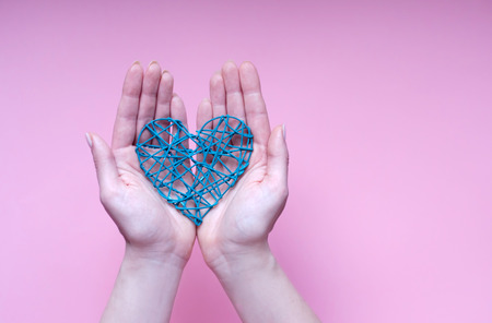 The heart of the blue wire in the palms of your hands on a lilac backgroundの写真素材