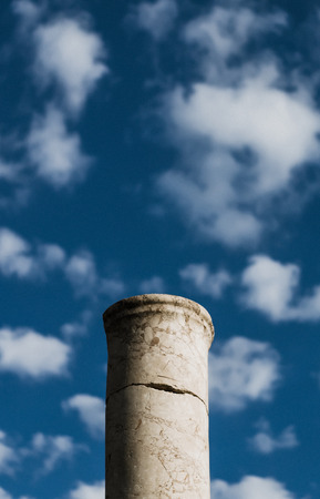Ancient column on the background of bright blue summer sky with clouds.の写真素材