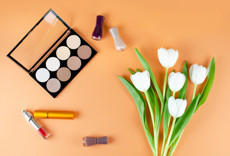 Cosmetics and flowers lies on a soft peach background. The contents of women's cosmetic bags. Visagisteの写真素材