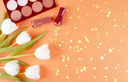 Cosmetics and flowers lies on a soft peach background. Contents of womens cosmetic bagの写真素材