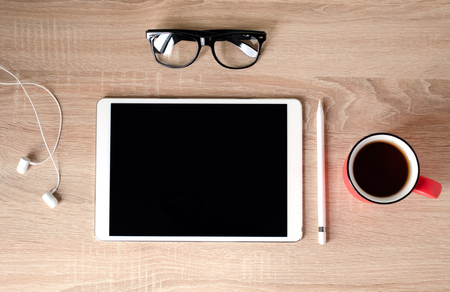 Wooden Desk. White tablet with black-rimmed glasses. Red Cup of tea.の写真素材