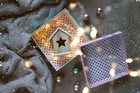 Wooden toy house with an asterisk in a gift box. Christmas background. The atmosphere of magic....