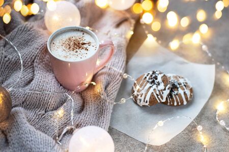 Cup of coffee with cinnamon. Christmas background with lights, warm knitted scarf. The atmosphere of coziness and Christmas.の写真素材
