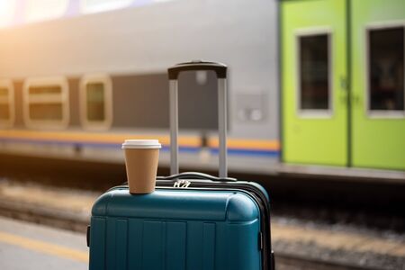 Suitcase with a Cup of coffee. Waiting for the train. Sunlight. Railway and train.の写真素材
