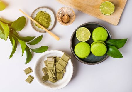 Still life with green products: macarons almond cakes, matcha tea, green vegan chocolate, lime. Gray background.の写真素材