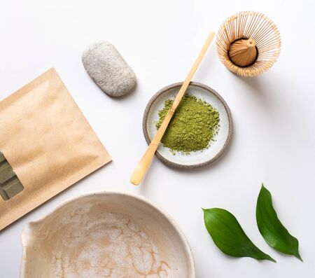 White ceramic spoon with tea of a Matcha on a light gray background. Matcha green tea in powder