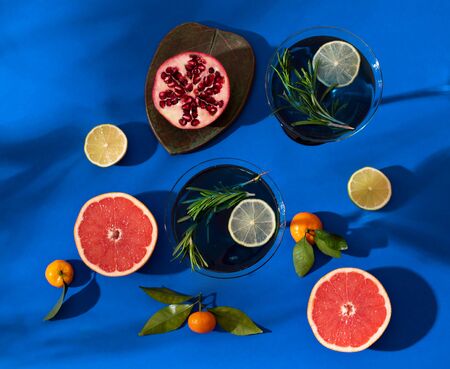Composition with citrus fruits on a bright blue background. Bright light, contrasting shadows. Juicy photo. Cocktail in a glass.の写真素材