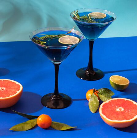 Composition with citrus fruits on a bright blue background. Bright light, contrasting shadows. Juicy photo.Cocktail in a glass.の写真素材