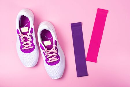 Women's white sneakers on a pink background. The view from the top.