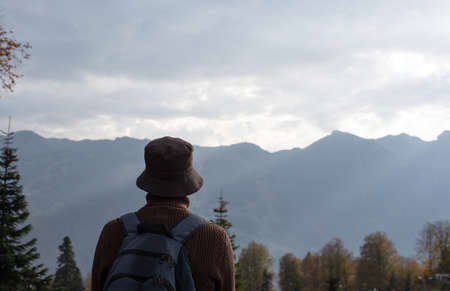 Young man from the back. Looks at the mountains. Beautiful nature. Sun ray.の写真素材