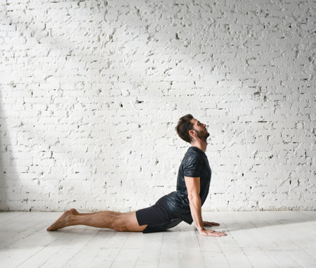 A young man is doing yoga. Yoga coach on a light background.の写真素材