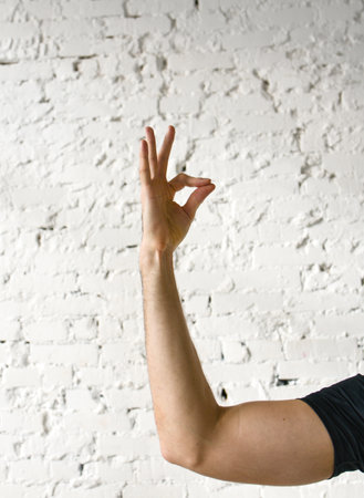 A gesture from yoga. A hand against a white brick wall.の写真素材