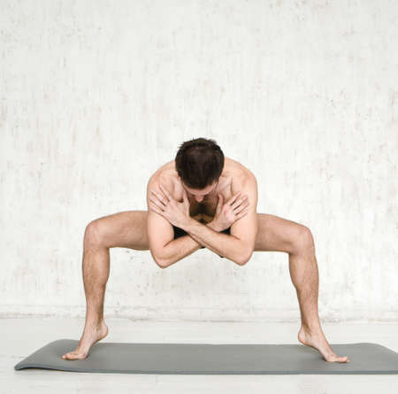 A young man is doing yoga. Yoga coach on a light background.の写真素材