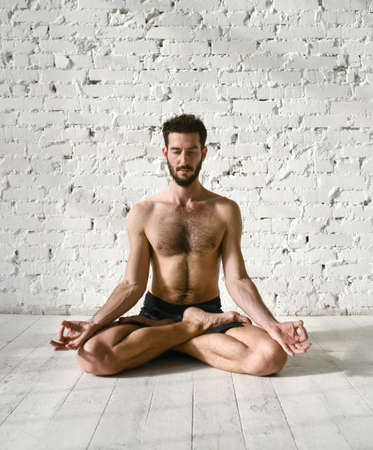 A young man is doing yoga. Yoga coach on a light background.の写真素材