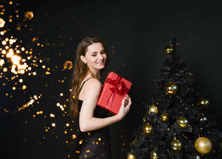 Beautiful young woman at the Christmas tree. An elegant woman.の写真素材