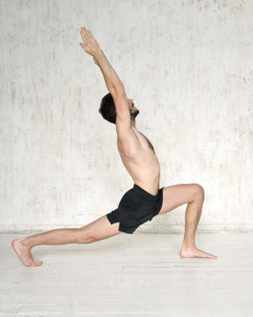 A young man is doing yoga. Yoga coach on a light background.