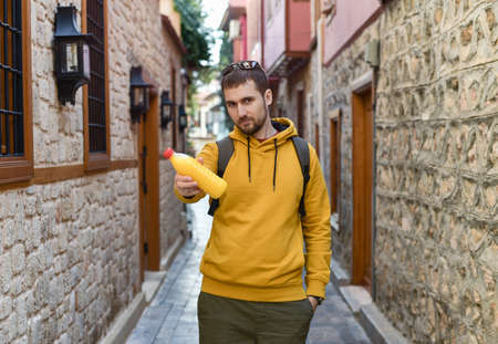 A young man in a yellow jacket with freshly squeezed orange juice. Healthy lifestyle.