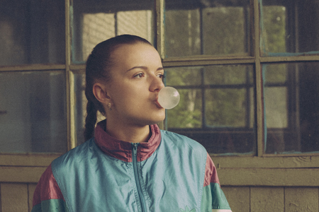 The girl in the nineties inflate the bubble of chewing and looking to the sideの写真素材