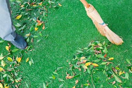 Working with a broom sweeps the lawn from the fallen leaves. The autumn season, working in the yard...