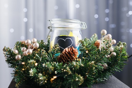 jar with stickers with a painted heart behind the Christmas wreath. In the background Christmas lightsの写真素材
