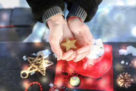 The girl holding a burning candle in the shape of a star. Preparing for the new year and Christmasの写真素材