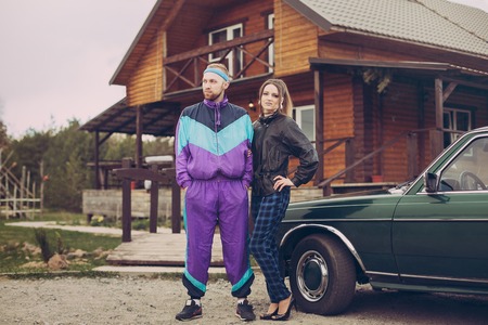 Guy and girl in clothes of the nineties, next to the old carの写真素材