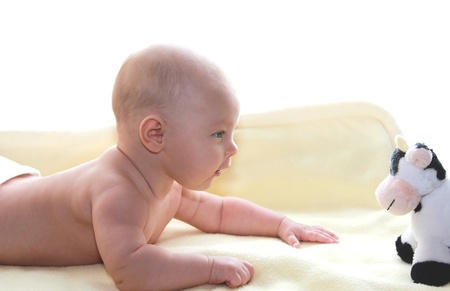 Beautiful baby girl looking at the toy isolated on white backgroundの写真素材