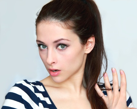 Closeup portrait of a surprised young woman holding hand the hair and looking with big eyes and opened mouth isolatedの写真素材