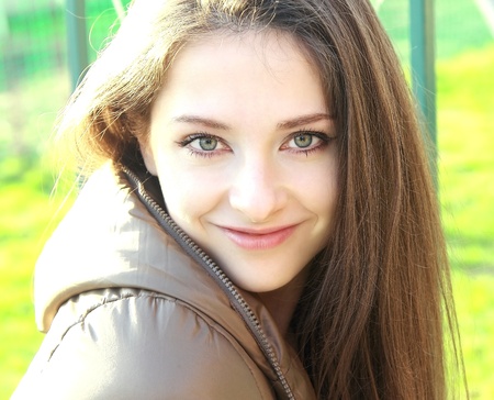 Beautiful smiling girl with long hair and green bright eyes on nature background  Closeup portraitの写真素材