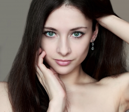 Fashion portrait of woman with sexy look holding face and long hair isolatedの写真素材