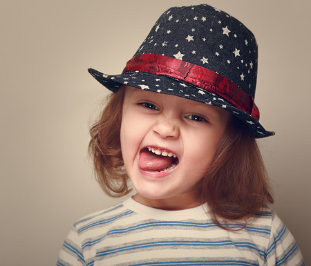 Happy grimacing kid girl in fashion hatの写真素材