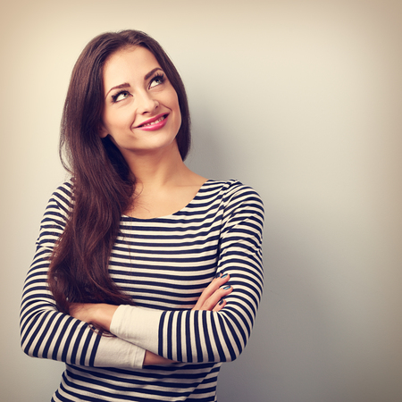 Happy thinking casual girl with folded hands looking up. Closeup vintage portrait with empty copy space Happy thinking casual girl with folded hands looking up. Closeup vintage portrait with empty copy space