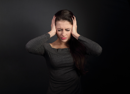 Stressed unhappy business woman closed ears the hands because not want the hear any sounds and noise on dark grey backgroundの写真素材