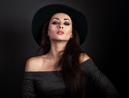 Expressive makeup woman in fashion elegant hat posing on dark shadow background. CLoseup portraitの写真素材