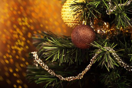 Beautiful Christmas green tree with ball on the branches on bright orange yellow background with empty copy spaceの写真素材
