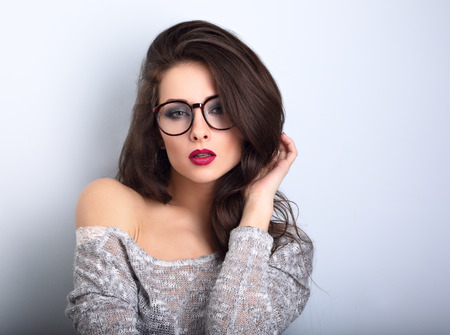 Beautiful sexy bright red lips makeup woman posing in gey blouse on blue background. CLoseup portraitの写真素材