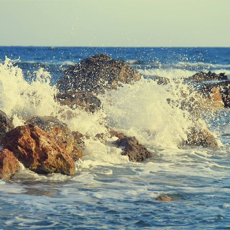 Beautiful sea wave background with rocky shore and foam. Contrast portrait. Toned vintage color