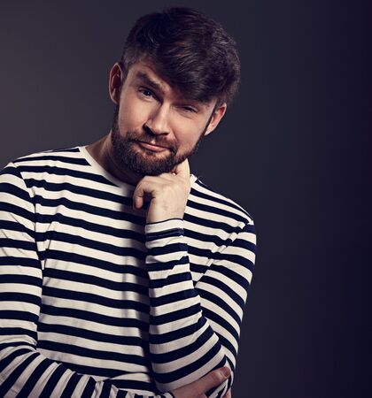 Bearded happy emotional man thininking about with fun grimacing face on grey background. Closeup portraitの写真素材