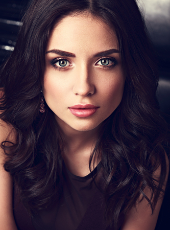 Beautiful makeup woman with pink lipstick, contrast eyebrow and long curly hair looking her big romantic blue eyes. Closeup toned vintage portraitの写真素材