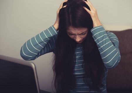 Unhappy woman with headache sitting near the laptop. Closeup portrait of business person on work. Hard dayの写真素材