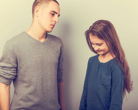 Young serious teen father have a dialog with his small school girl daughter. Happy joyful emotions on toned vintage color background. Closeupの写真素材