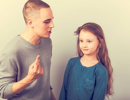 Young serious teen father have a dialog with his small school girl daughter. Happy joyful emotions on toned vintage color background. Closeupの写真素材