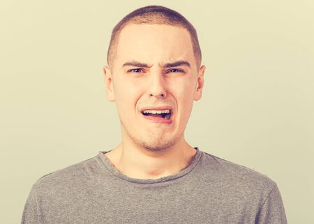 Unhappy crying man with grimacing face. Closeup studio portrait on vintage toned background