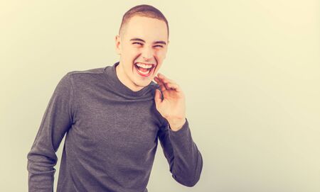 Happy fun young man laughing with wide opened mouth in casual clothing on vintage color toned background with empty copy space.の写真素材