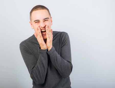 Happy fun young man laughing with wide opened mouth in casual clothing on vintage color toned...