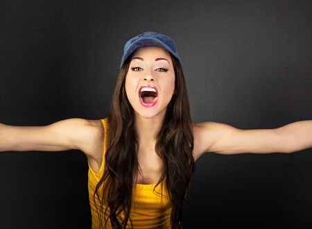 Happy excited woman in summer clothing crying with wide open mouth and want to hug all the world on gray background. Closeup portraitの写真素材