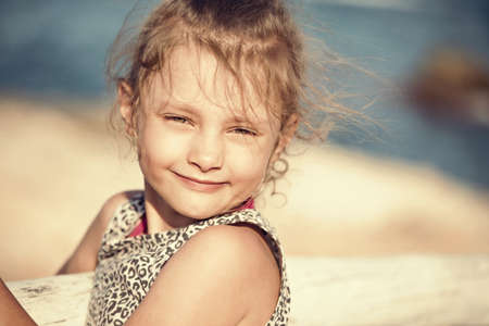 Happy kid girl relaxing and joying on blue sea background and vacation sky. Closeup holidays outdoors portraitの写真素材