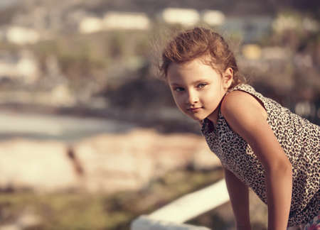 Happy kid girl relaxing and joying on vacation holidays. Closeup outdoors portrait of beautiful view...